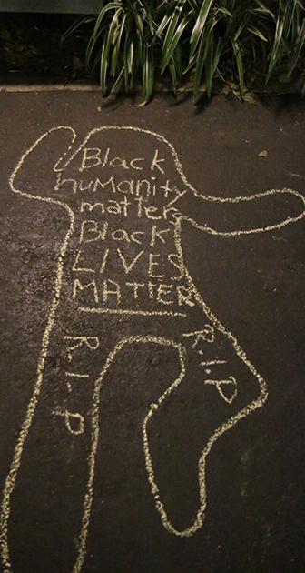 Students write on the pavement as part of a "die-in" on McAllister Drive.