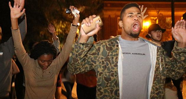 Students raise their hands, chanting Hands up, dont shoot.