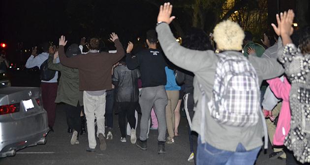 Protestors march with arms raised down McAllister Drive.