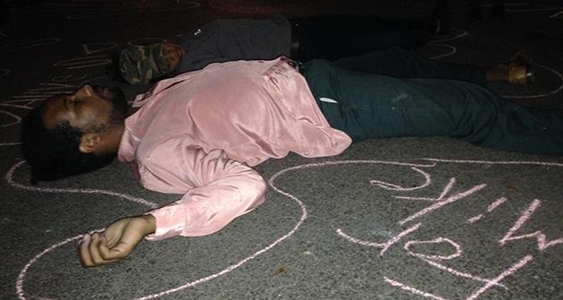 Students write on the pavement as part of a die-in on McAllister Drive.