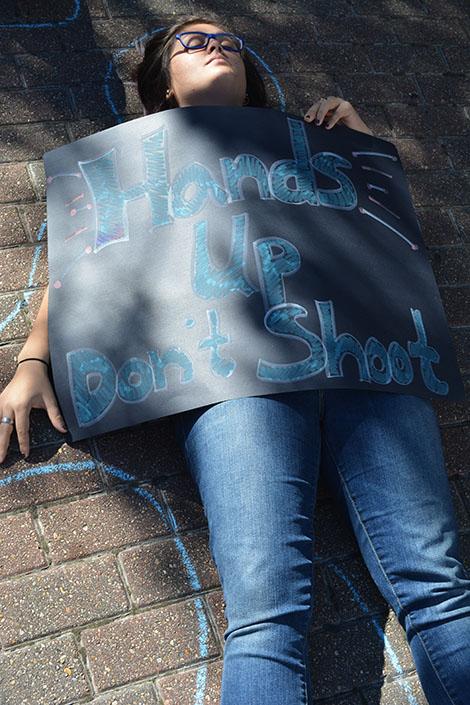 Marion Boreros lies on the ground with her Hands Up Dont Shoot sign for the die-in protest.
