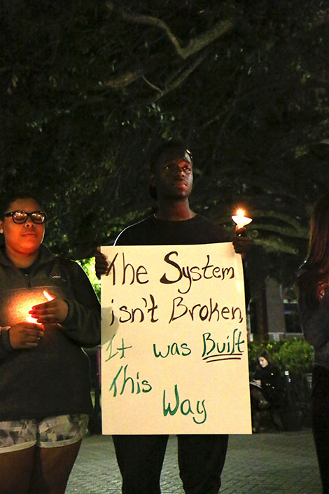 Bryston Ivey, a SUNO student, holds up a sign at the vigil.