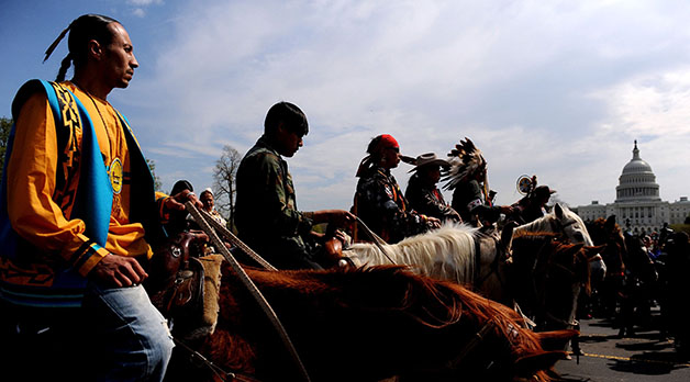 Native Americans ride on horseback around the Mall in Washington, D.C. to protest the Keystone XL pipeline. Its construction inflicts environmental injustices on the indigenous.