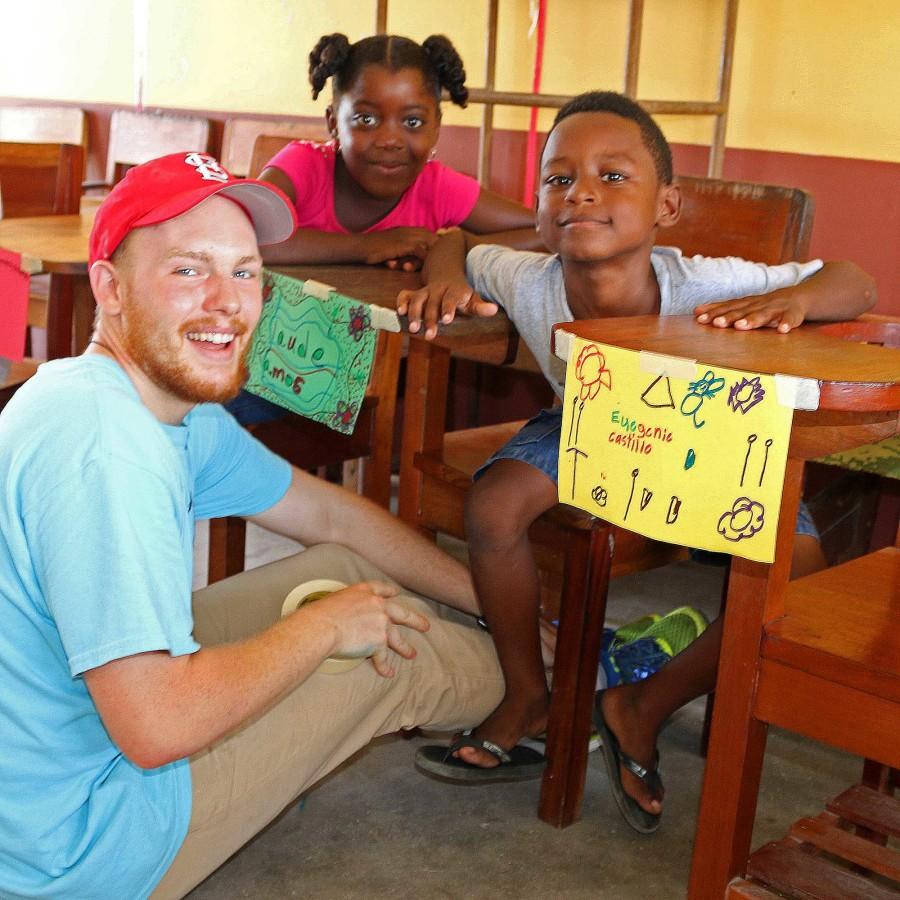 Brendan Dodd, management senior, poses with children during the summer 2015 Iggy Vols trip in Dagriga, Belize. The volunteers spent their time teaching children and learning about the culture