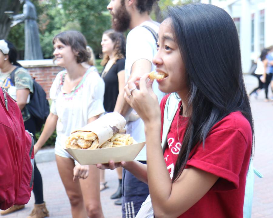 Sandra Nguyen, a biology junior, eats a waffle from the Ironsides Waffles food truck in the Peace Quad. The truck will come to Loyola every Wednesday during the window. Photo credit: Zach Brien