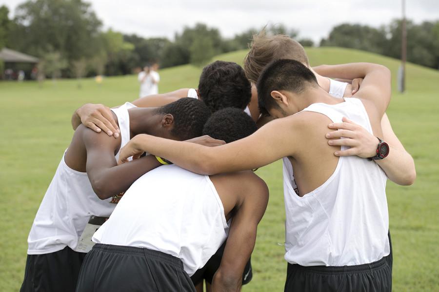 The mens cross country team huddles together before competing in the All-State Sugarbowl Invitational hosted by Loyola University. Both the mens and the womens team placed in the top five at their only home meet of the season, and are looking to continue to build on that success throughout the year. Photo credit: Courtesy of the Athletic Department