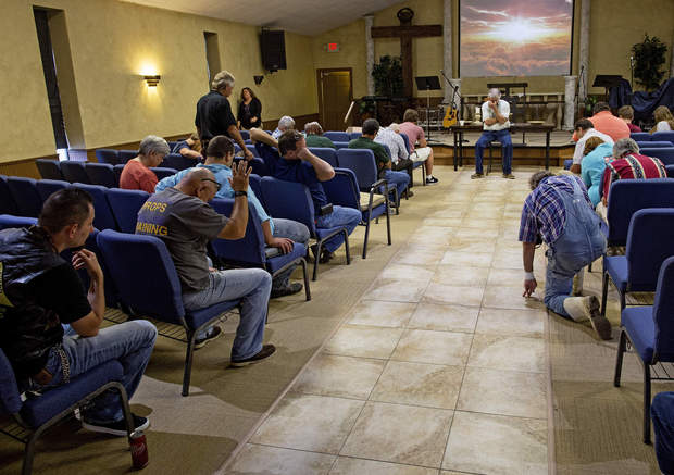 Members of the South Walker Baptist Church led by pastor Mark Carroll, center, pray at the conclusion of what is normally a time for Bible study, but which became an informal talk about experiences during the flood in Walker, La., Sunday, Aug. 21, 2016. The church was an island of high ground in a community flooded with 4-5 feet of water a week earlier. During and since the flood the church is serving as a shelter and food distribution point for the community. (AP Photo/Max Becherer)