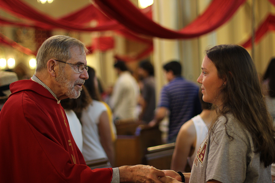 The Rev. Ed Vacek, S.J., greets a student at the Mass of the Holy Spirit Sept. 8.  The Mass is a Jesuit tradition dating to the sixteenth century. Photo credit: Tasja Demel