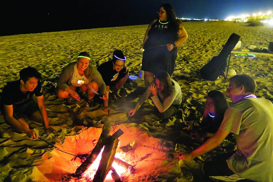 NOLA Wesley retreaters roast marshmallows on the beach in Biloxi, Mississippi. The group held its fall retreat at the Seashore United Methodist Assembly there. Photo credit: Courtesy of Cheryl Guyton