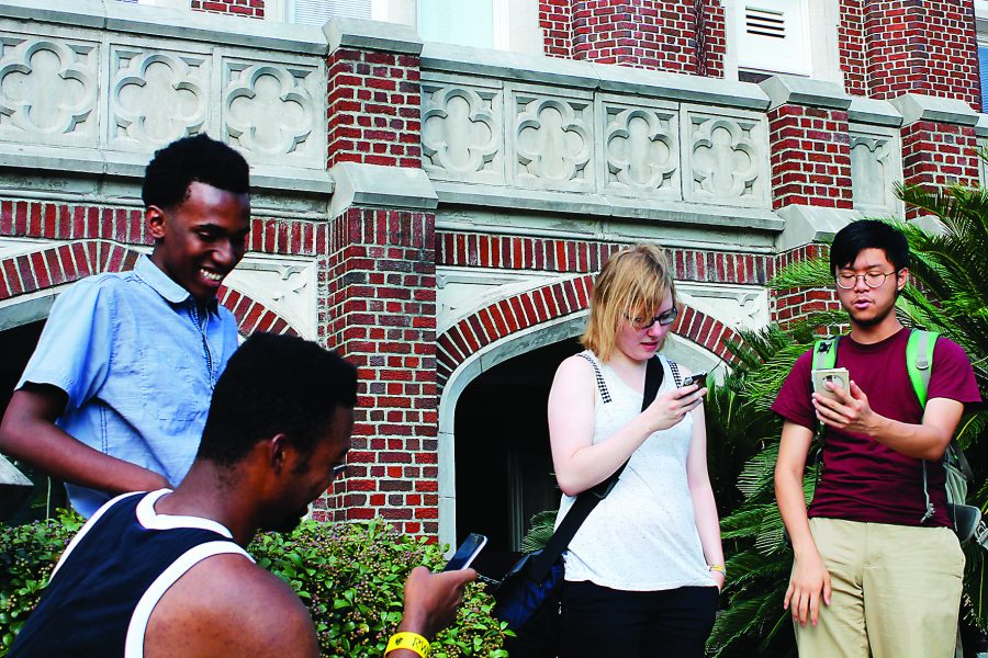 Trainers (from left to right) Staffon Turley, Malik Thompson (bottom left), Tasja Demel, and Cyril Ma check their Pokédex to see which wild Pokémon are left for them to catch. Loyola University and Audubon Park, a PokéStop, are great places to find Pokémon. Photo credit: Alliciyia George