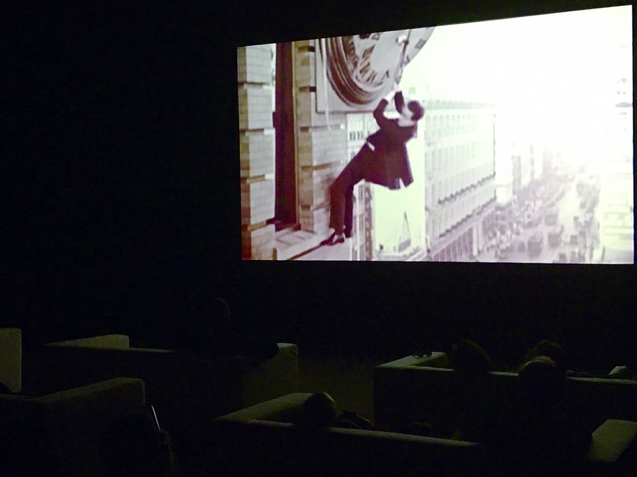 Viewers watch The Clock, a 24 hour film installation that compiles clips from movies telling the time to complete a daylong cycle. The installation is playing in New Orleans through early December. Photo credit: Davis Walden