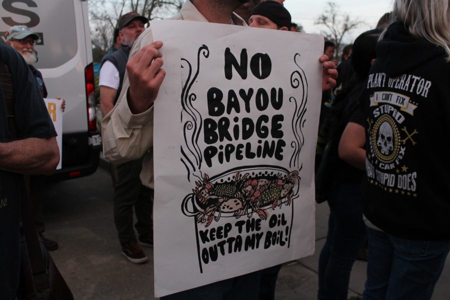 A protester holds up a sign prior to a hearing for the Bayou Bridge pipeline. Speakers at the hearing were often interrupted by protests from the crowd.