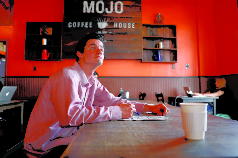 Caleb Beck sits inside Mojo Coffee House. He is one of many who come to enjoy the establishment’s food and drinks as well as calm working environment. Photo credit: Barbara Brown