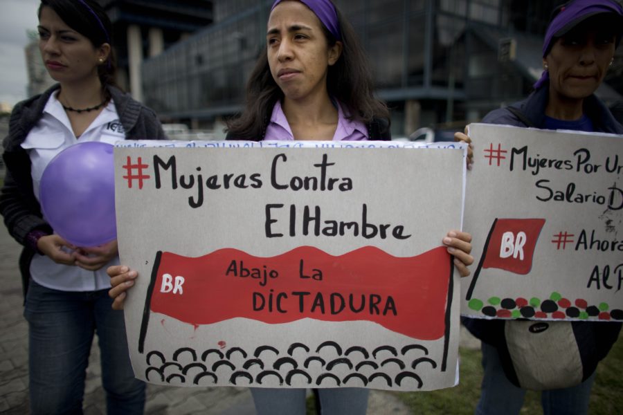 A woman holds up a sign that reads in Spanish  Women against hunger, down with the dictatorship during a protest against violence against women, in Caracas, Venezuela, Wednesday, March 8, 2017. Thousands of women are marching to commemorate International Women’s Day around the world. (AP Photo/Ariana Cubillos)