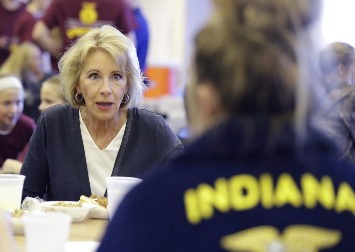 In this Sept. 15, 2017 photo, U.S. Secretary of Education Betsy DeVos talks with Gracie Johnson during a hog roast before a high school football game between Eastern Hancock and Knightstown in Charlottesville, Ind. DeVos uses a private jet to fly around the country to tour schools and attend other work events, the Associated Press has learned.  (AP Photo/Darron Cummings) Photo credit: Associated Press