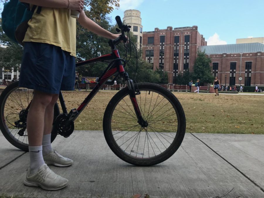 A student walks his bike to the bike rack by the West Road garage. Many students commute to campus via bike daily, one that includes numerous potholes, tight one-way streets and oblivious drivers. Photo credit: John Casey