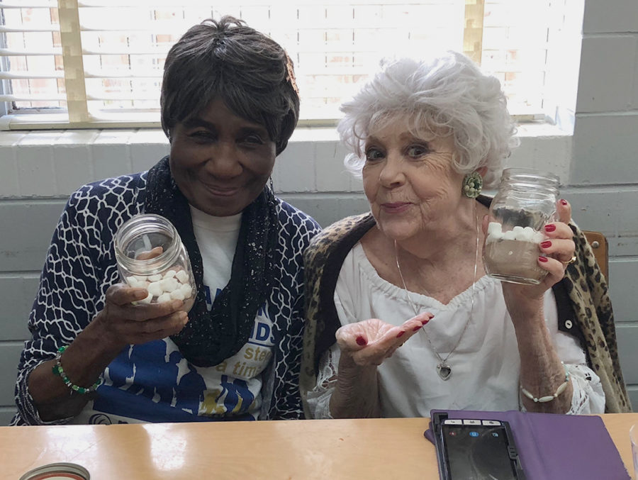 Two locals at the Uptown Shepherd’s Center on Oak Street boast their mason jars full of hot chocolate mix and marshmallows and enjoy spending time with Loyola students during a LUCAP volunteer visit. Courtesy of LUCAP