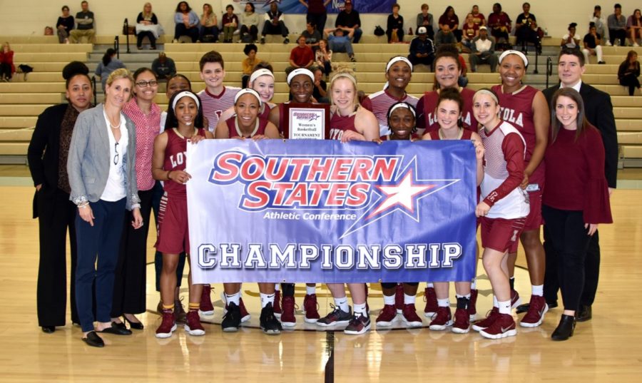 The+2017-2018+Loyola+womens+basketball+team+poses+with+the+championship+banner+after+their+66-53+win+versus+Martin+Methodist.+The+program+celebrates+their+third+championship+in+four+years.+Photo+credit%3A+Loyola+University+Athletics