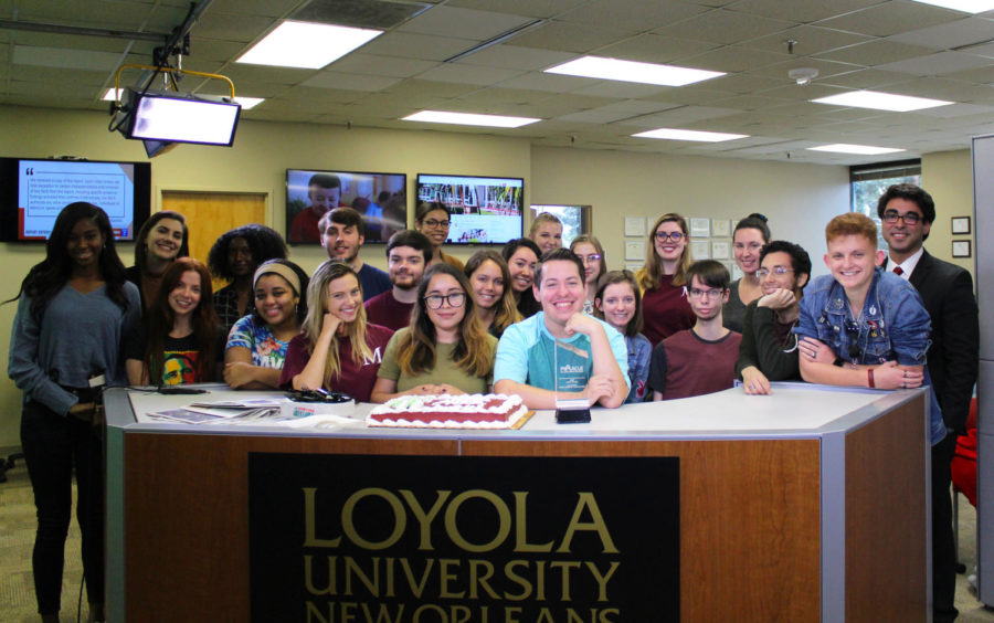 The 2018 Fall staff of The Maroon sits at the anchor desk with their 2018 Pinnacle award for Best College Media Outlet.