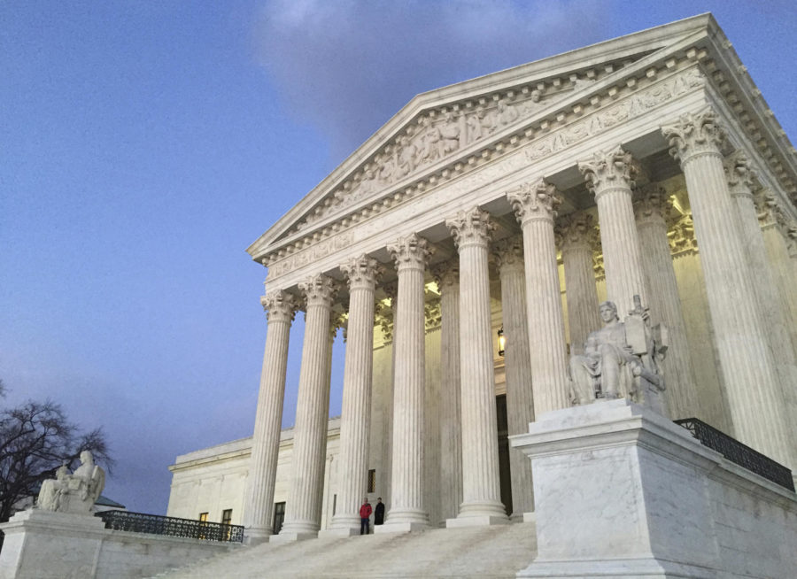 FILE - In this Feb. 13, 2016, file photo, people stand on the steps of the Supreme Court at sunset in Washington. A sharply divided Supreme Court is allowing the Trump administration to go ahead with its plan to restrict military service by transgender men and women while court challenges continue.  (AP Photo/Jon Elswick, File)