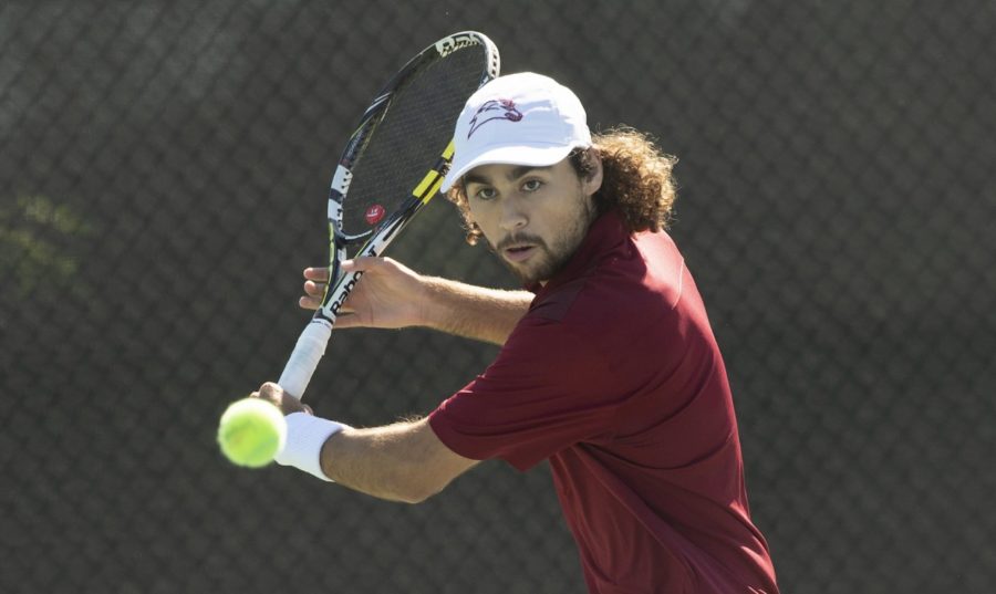 Biology senior Sebastian Gomez hits a tennis ball during warm ups. Both men and women's teams won two matches in a double-header. Photo credit: Loyola University Athletics