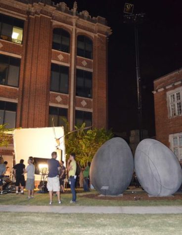 A film crew sets up and tests lighting for