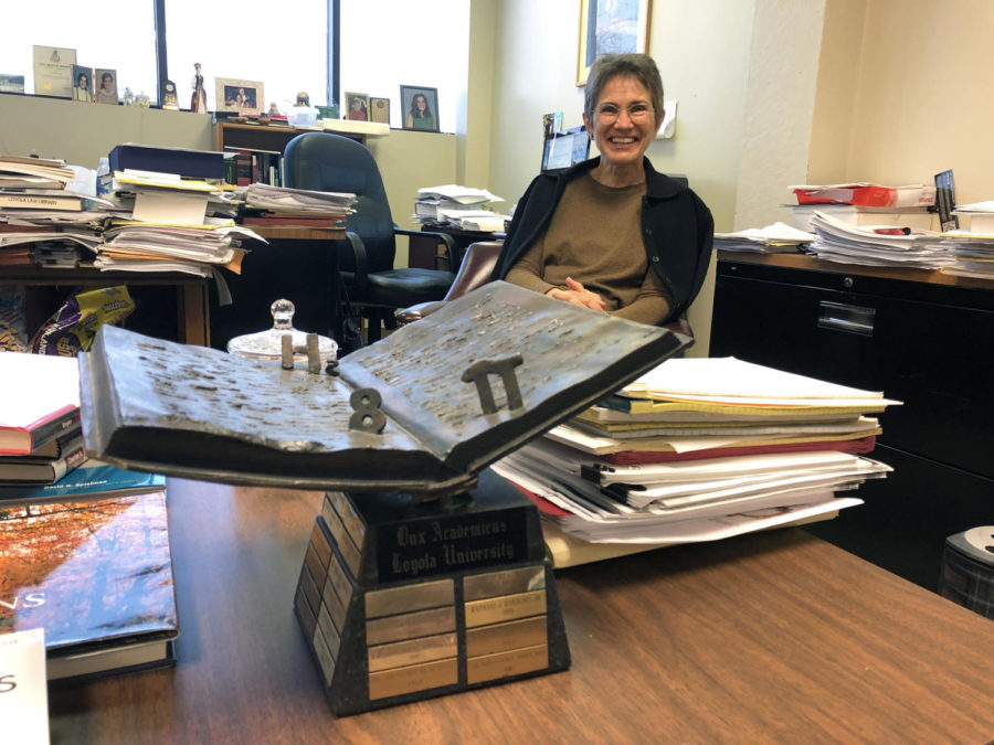 Isabel Medina, law professor, sits in her office surrounded by her work and the Dux Academicus award Feb. . The annual award recognizes a Loyola faculty member for their superior scholarship and teaching. Photo credit: Erin Snodgrass