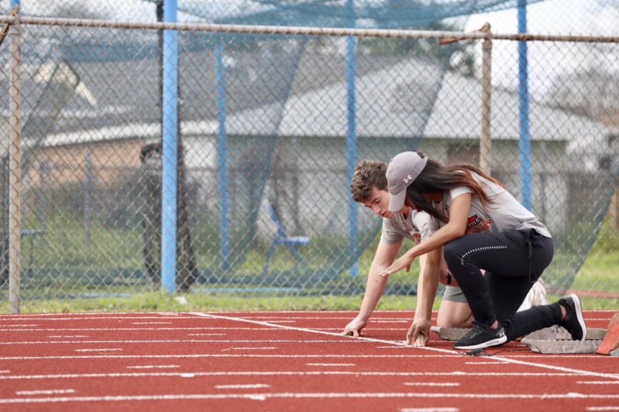 Track+and+field+assistant+coach+Amani+Bryant+helps+a+sprinter+with+his+exercises.+The+track+program+practices+at+East+Jefferson+High+School.+Photo+credit%3A+Andres+Fuentes