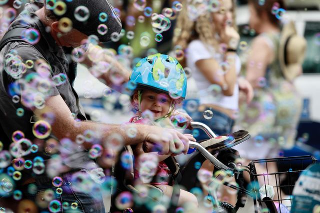 A father rides with his daughter in a bicycle through bubbles on Decatur Street. The French Quarter Fest prides itself on its family-friendly atmosphere.