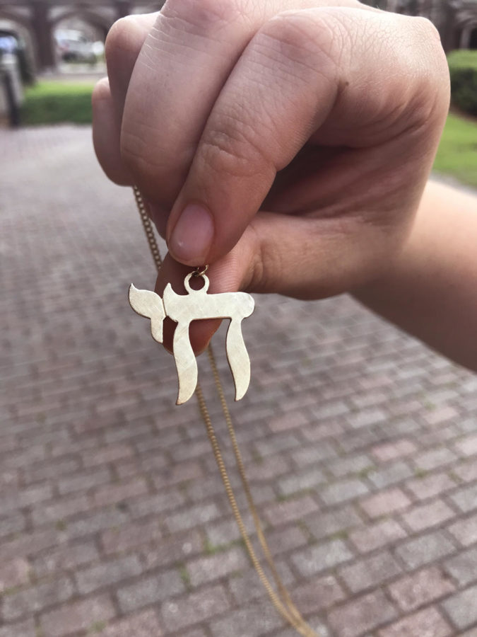 Grace Quisenberry, political science junior, holds up her necklace displaying the hebrew symbol chai on May 1, 2019. The word means life and is a commonly used Jewish symbol Photo credit: Rose Wagner