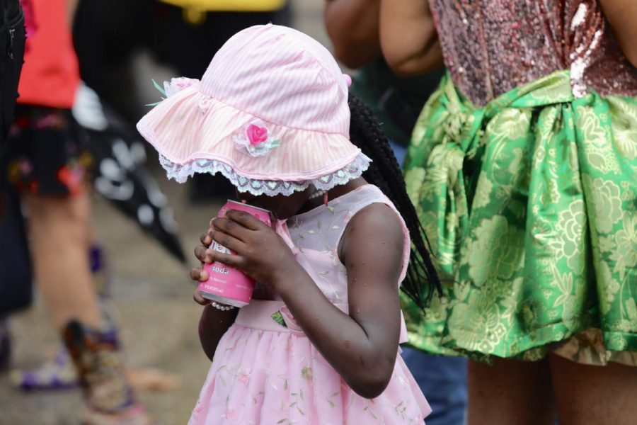 A baby doll cools down with a drink during Art Neville's second line procession on July 30, 2019. Photo credit: Andres Fuentes