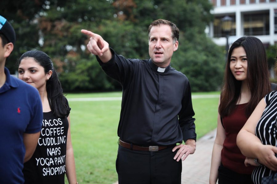 Rev. Justin Daffron, S.J., walks with students around campus. Daffron will be serving as Loyola's interim president. 