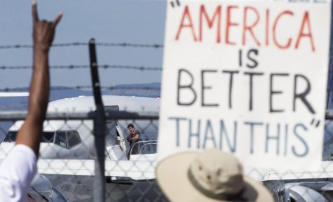 An ICE detainee waves at people chanting and holding signs along the fence while boarding a Swift Air flight on Tuesday, Aug. 20, 2019 at McCormick Air Center in Yakima, Wash. (Evan Abell / Yakima Herald-Republic via AP)/Yakima Herald-Republic via AP)