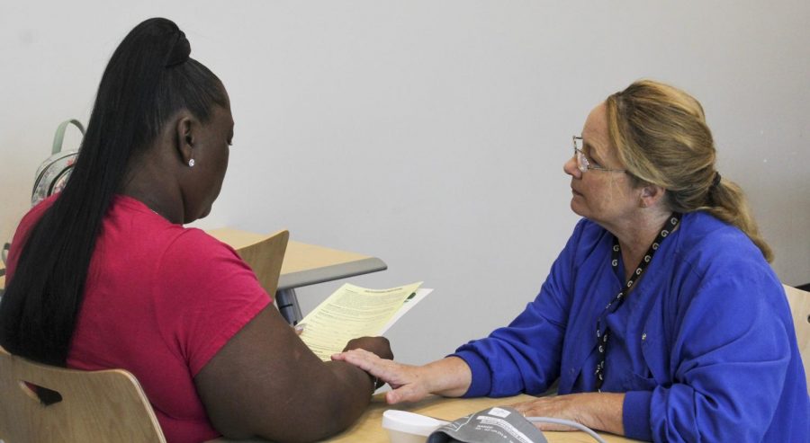 Registered nurse Kathe Haase (right) reviews Shannon Jackson’s (left) paperwork with her following a blood pressure screenings. These screenings are provided for free to the public by the city and Touro as part of the Healthy Women New Orleans initiative. Photo credit: Shadera Moore