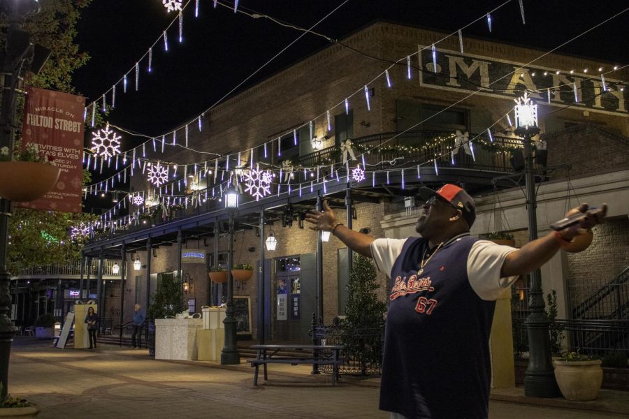 Pierre Wilbourn, a New Orleans resident, enjoys the light display as he awaits the snowfall on Fulton Street. Each year, thousands of people visit Miracle on Fulton Street to experience the faux snow and beautiful light display. Photo credit: Caitlyn Reisgen