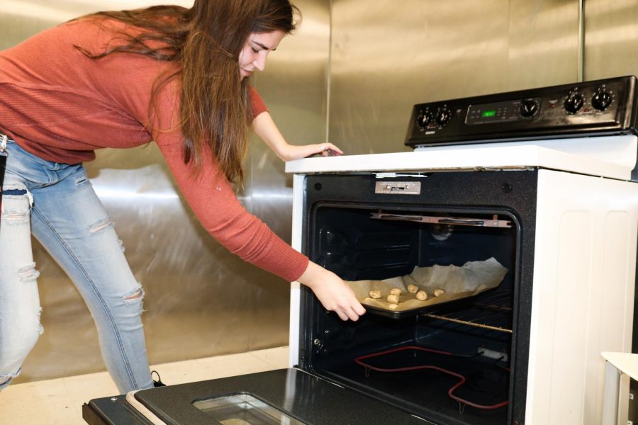 A student is using the new oven of the Carrolton kitchen to bake.