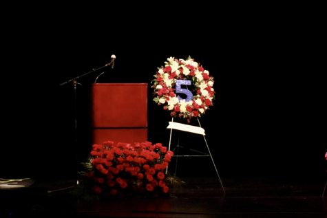 A flower display is arranged into the number 5 and sits next to a podium.