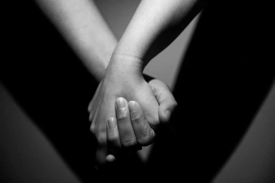 A black and white photo of two hands holding.