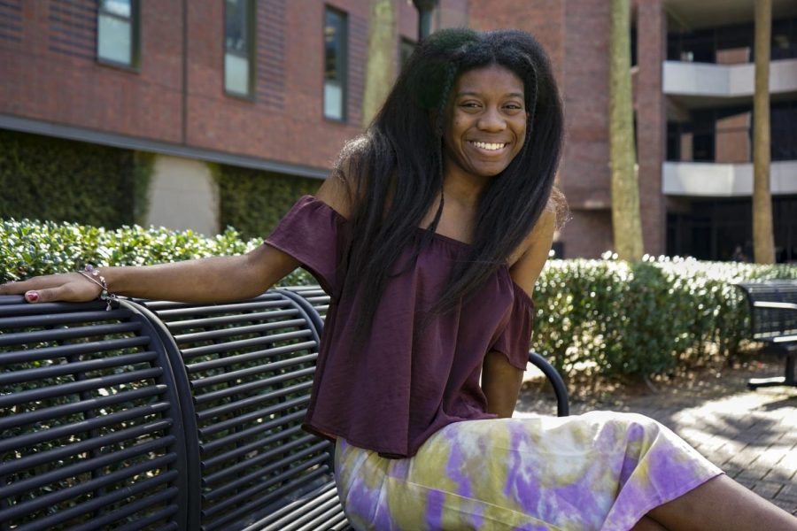 Student Noa Jamir sitting and smiling on bench.