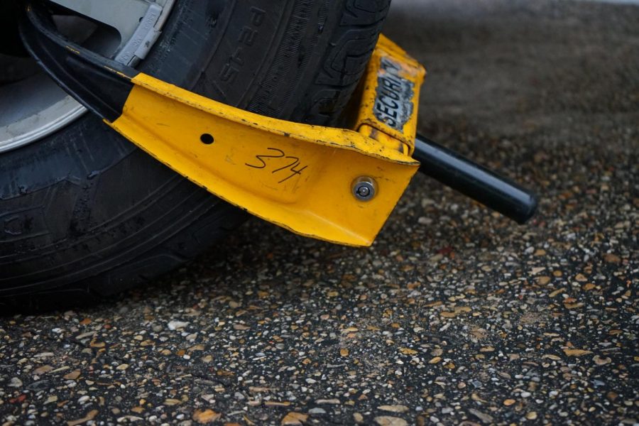 A car's tire sits booted in the horseshoe on February 12, 2020. Loyola police have said they will start cracking down on faculty parking. Photo credit: Cristian Orellana