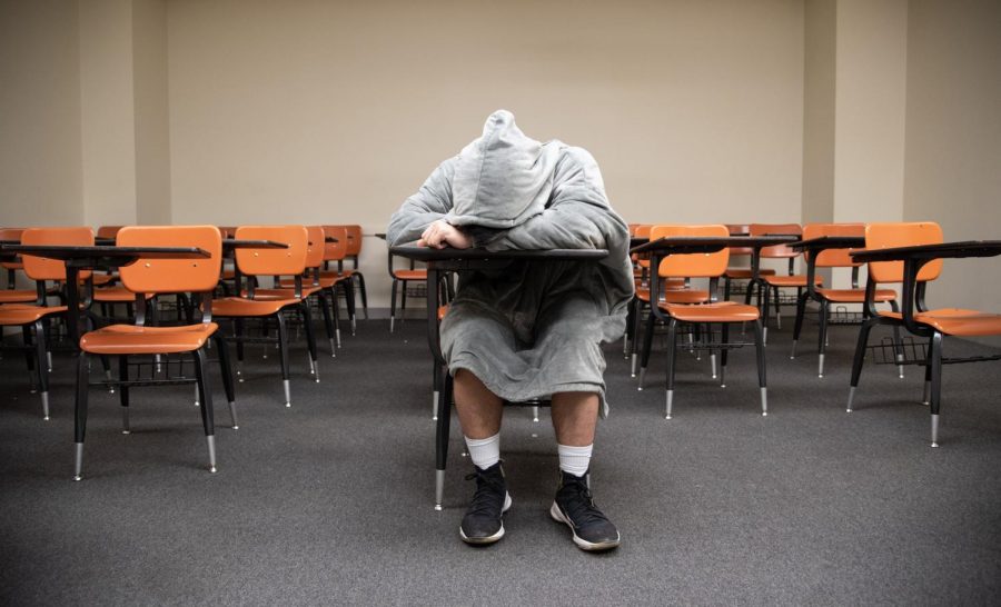 A student is asleep in an empty classroom