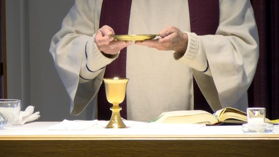 A+priest+serves+communion+during+mass.