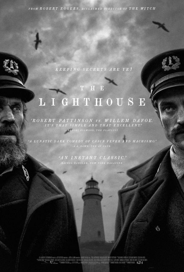 Actors Willem Dafoe and Robert Pattinson stand besides each other dressed in uniforms with the titular lighthouse standing in the background.