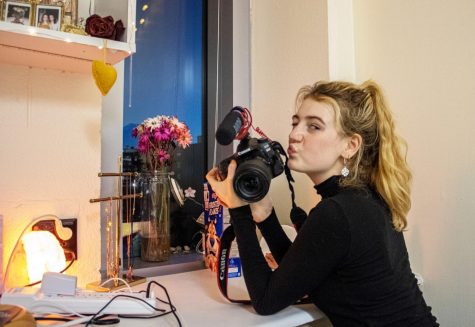 Haley Raines poses in her dorm with the camera she uses to film her Youtube videos. Her channel focuses on documenting how she practices sustainable living being a vegan college student. Photo credit: Caitlyn Reisgen