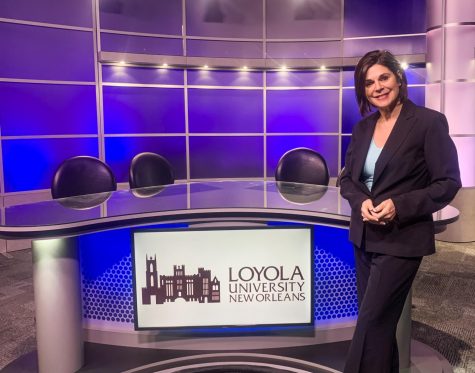 Sonya Duhé poses in front of the anchor desk in Studio A at Loyola.