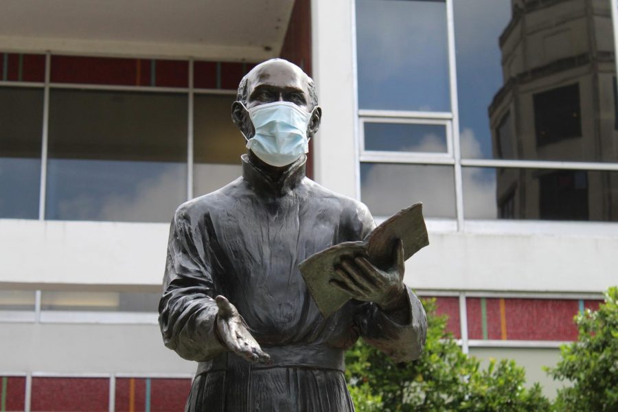 The statue of St. Ignatius of Loyola wears a protective face mask in the Peace Quad on Loyola's campus June 2020.