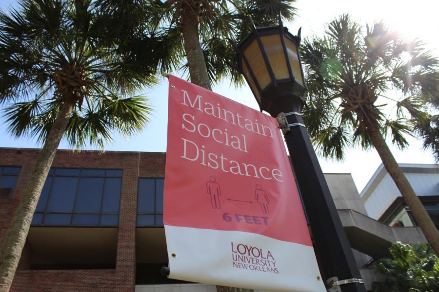 A sign promoting social distancing hangs from a lamppost in Palm Court Aug. 3. Loyola is offering free on-campus testing in an effort to prevent the spread of COVID-19. Photo credit: Alexandria Whitten