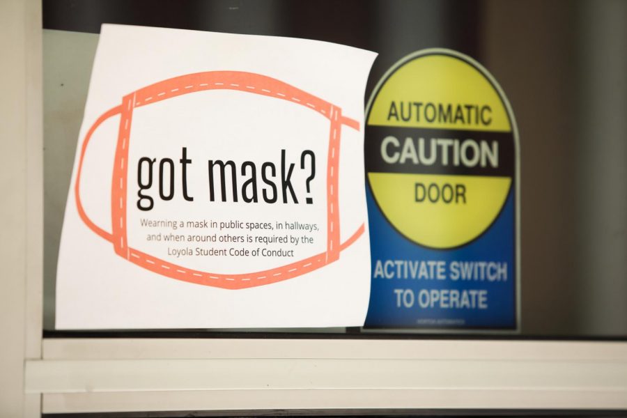 A sign with instructions to wear a mask while in on-campus public spaces hangs on a front door to Biever Hall on Thursday, August 20. The university has installed signage across campus with information related to COVID-19 policies. 