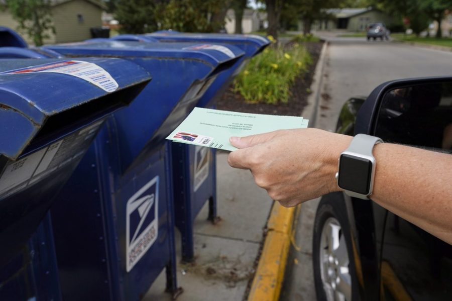 FILE - In this Tuesday, Aug. 18, 2020, file photo, a person drops applications for mail-in-ballots into a mail box in Omaha, Neb. U.S. Postal Service warnings that it can’t guarantee ballots sent by mail will arrive on time have put a spotlight on the narrow timeframes most states allow to request and return those ballots. (AP Photo/Nati Harnik, File) Photo credit: Associated Press