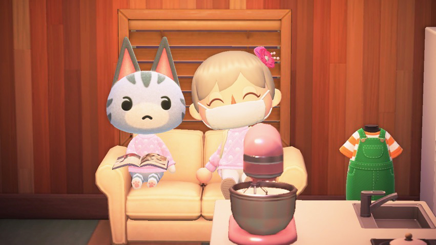 A screenshot from Animal Crossing shows two characters sitting on a couch